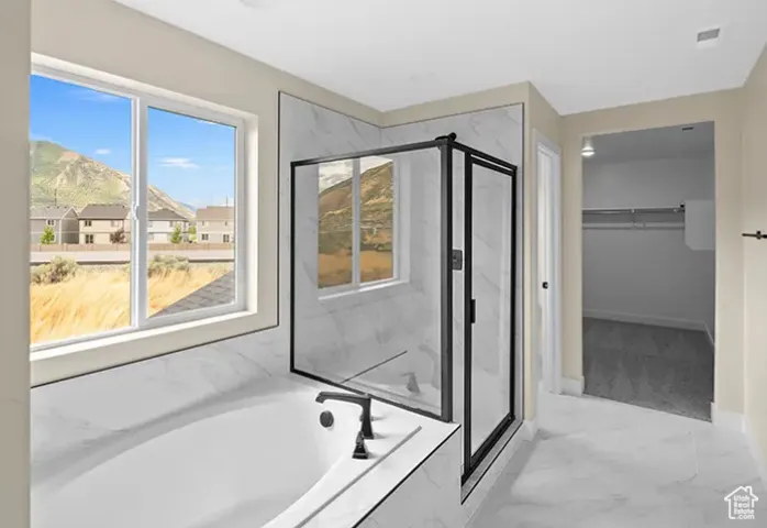 Bathroom featuring a marble finish shower, marble look tile flooring, a garden tub, and a spacious closet