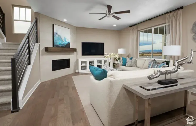 Living room featuring a fireplace, wood finished floors, stairway, ceiling fan, and recessed lighting