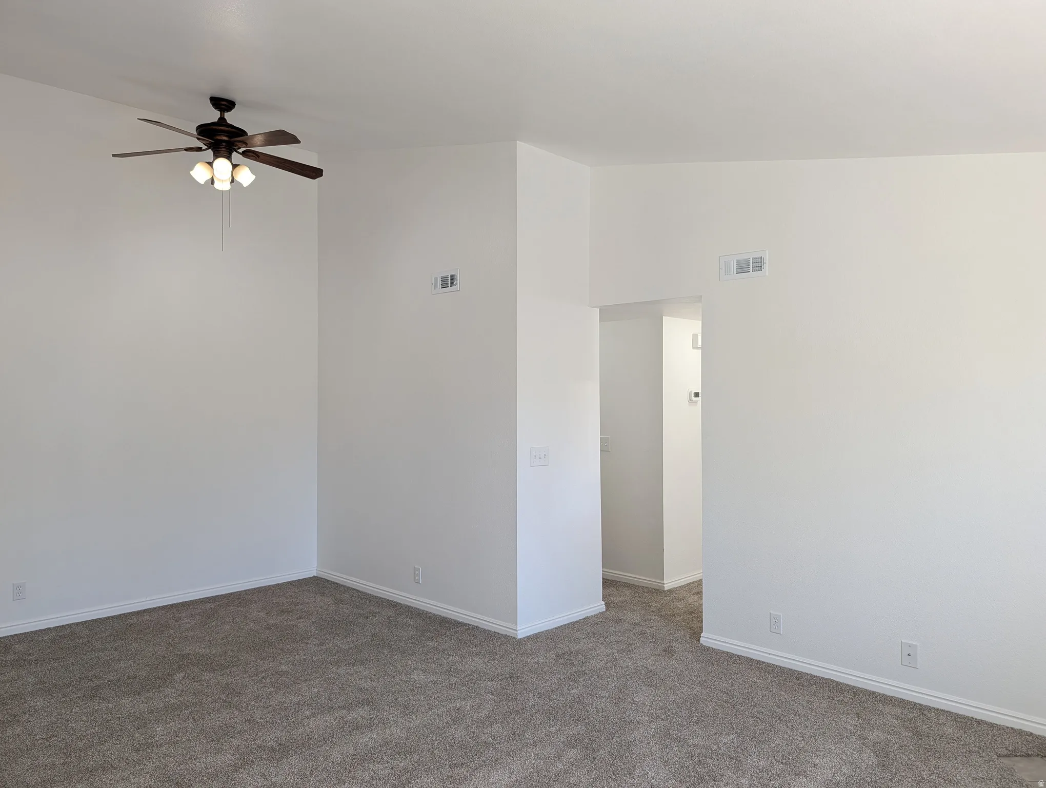 Spare room featuring a ceiling fan and dark colored carpet