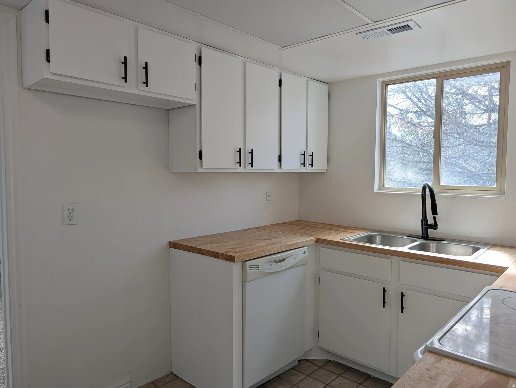 Kitchen with white cabinets, white appliances, and light tile patterned floors