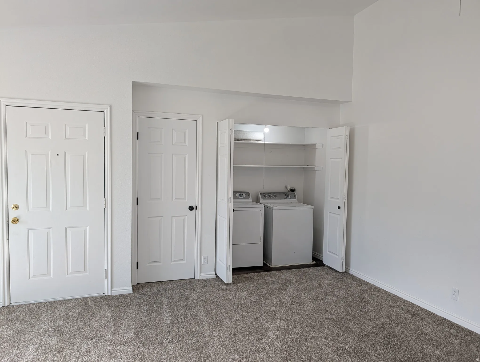 Laundry area with dark colored carpet and washer and dryer