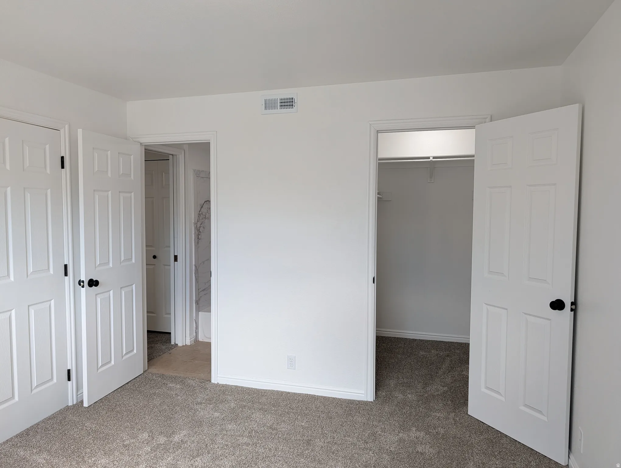 Unfurnished bedroom with a walk in closet and light carpet