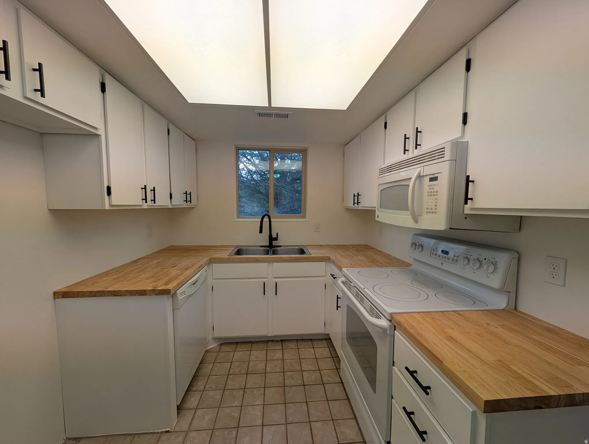 Kitchen with white appliances, light countertops, and white cabinets