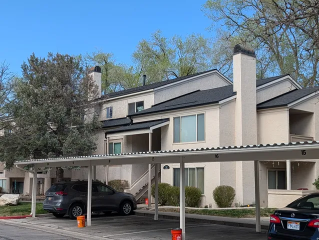Back of property with a chimney, stucco siding, and covered parking