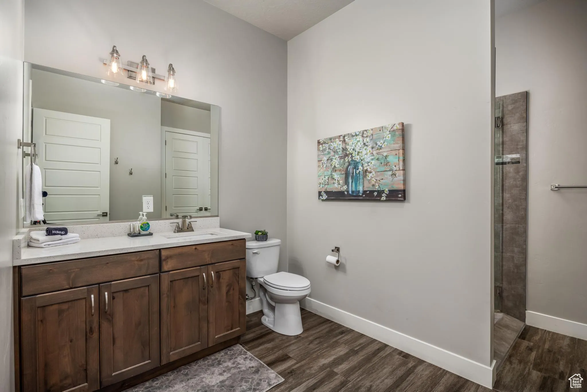 Full bathroom featuring vanity, dark wood finished floors, and a tile shower