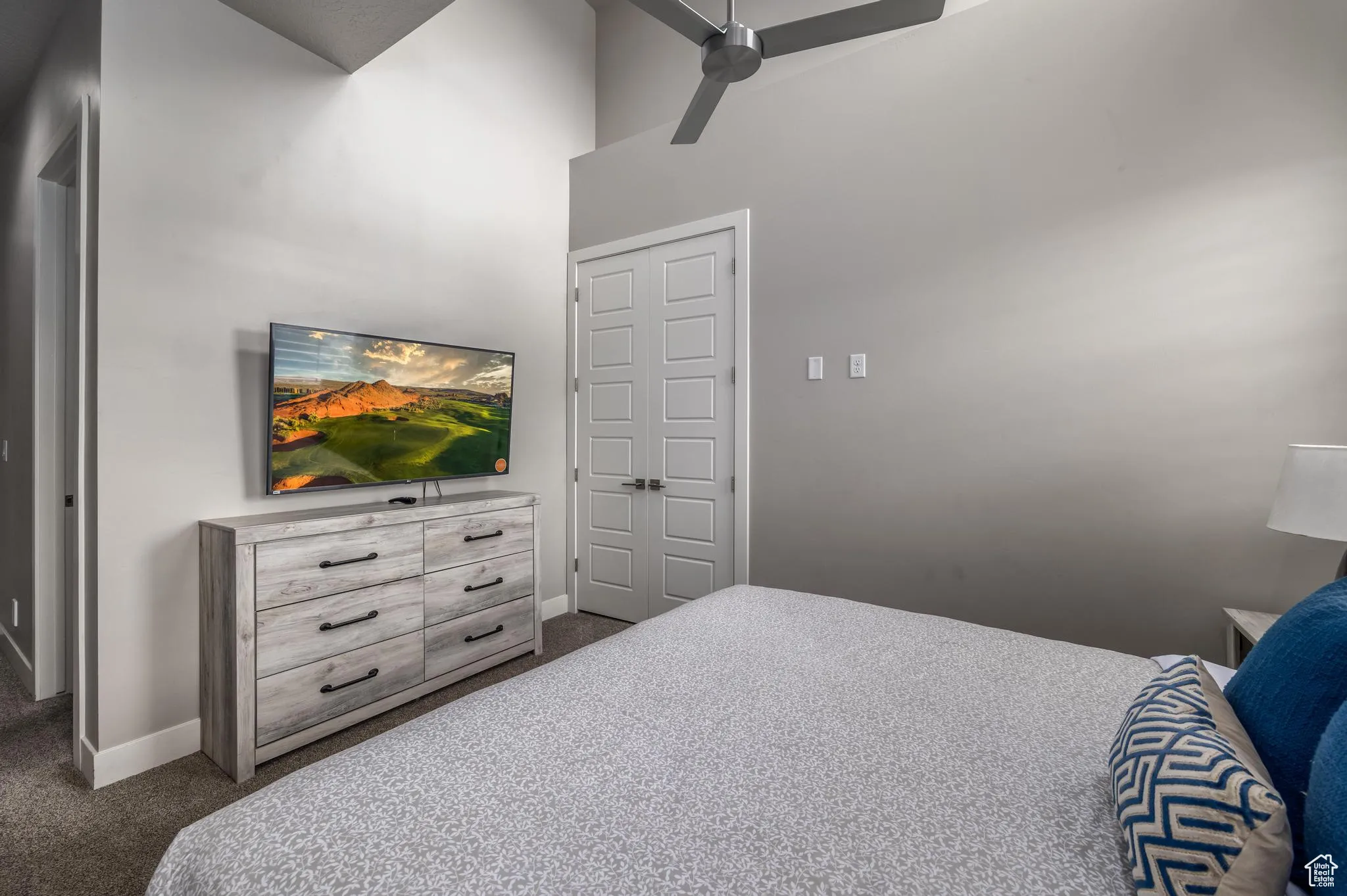 Bedroom with carpet, ceiling fan, and a high ceiling