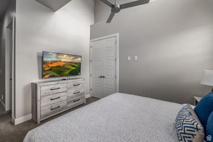 Bedroom with carpet, ceiling fan, and a high ceiling
