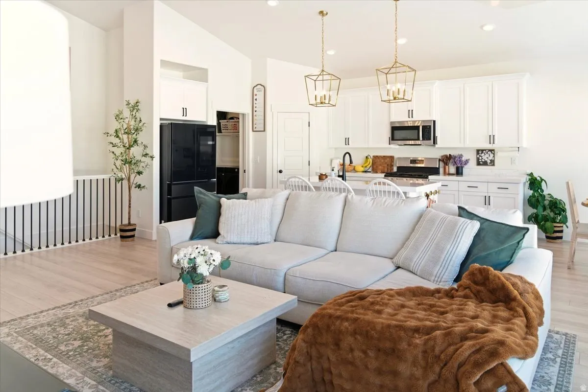 Living area featuring vaulted ceiling, light wood-style flooring, and recessed lighting