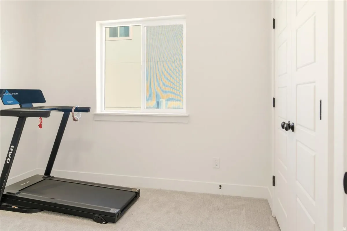 Exercise area featuring baseboards and light colored carpet