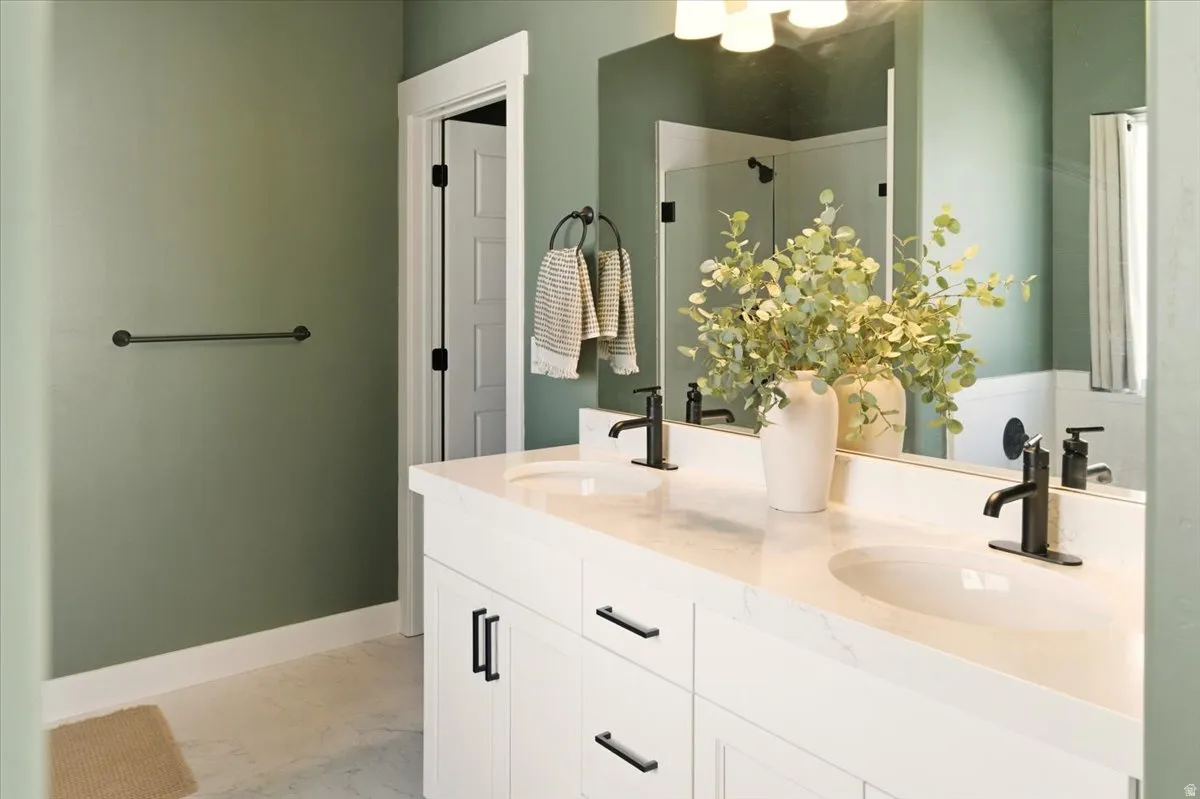 Bathroom featuring double vanity, light marble finish flooring, and a shower stall