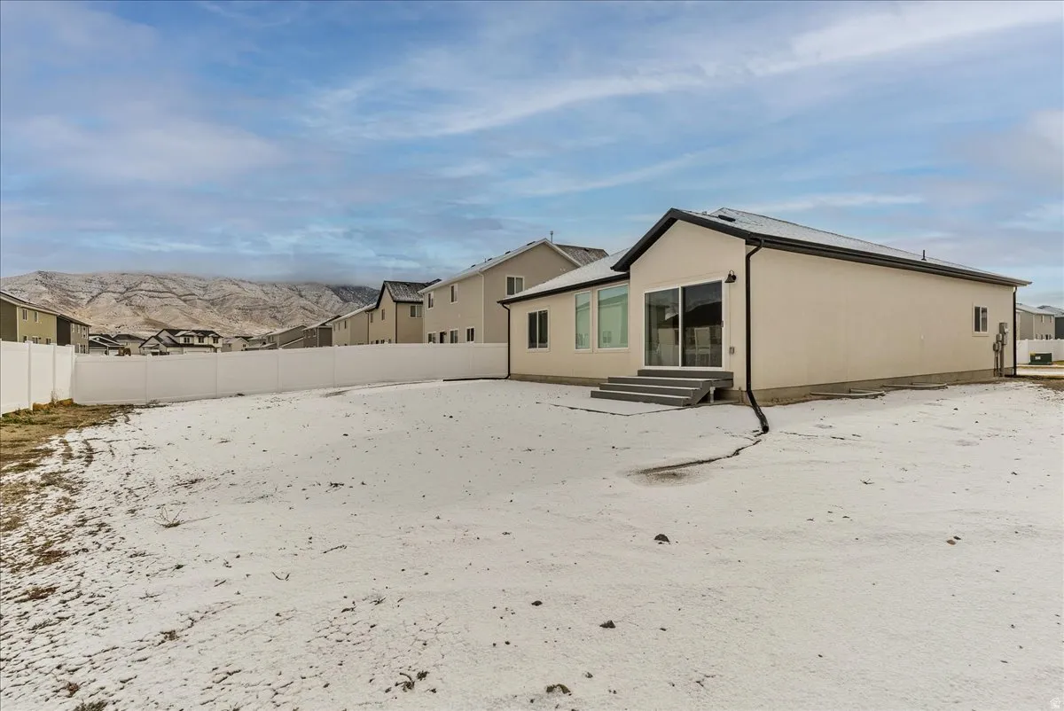 Snow covered rear of property featuring a fenced backyard and entry steps