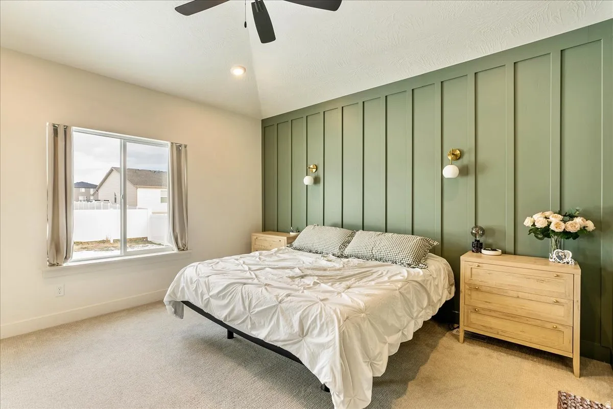 Bedroom with a decorative wall, carpet floors, a ceiling fan, and vaulted ceiling