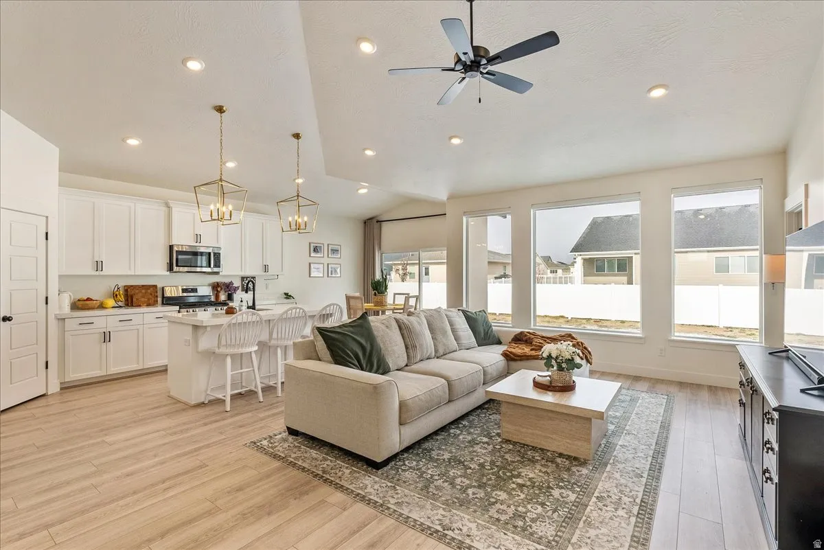 Living room featuring vaulted ceiling, light wood finished floors, a ceiling fan, and recessed lighting