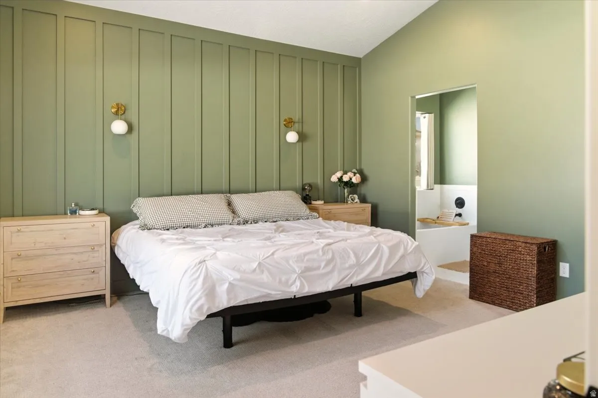 Bedroom featuring a decorative wall, vaulted ceiling, and carpet