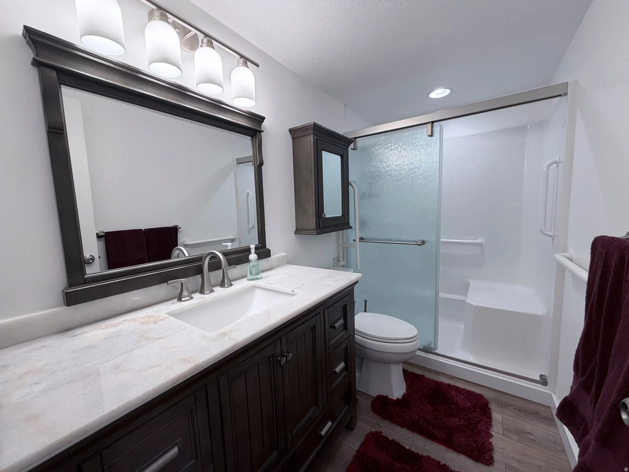 Full bathroom with vanity, a shower stall, and dark wood-style flooring