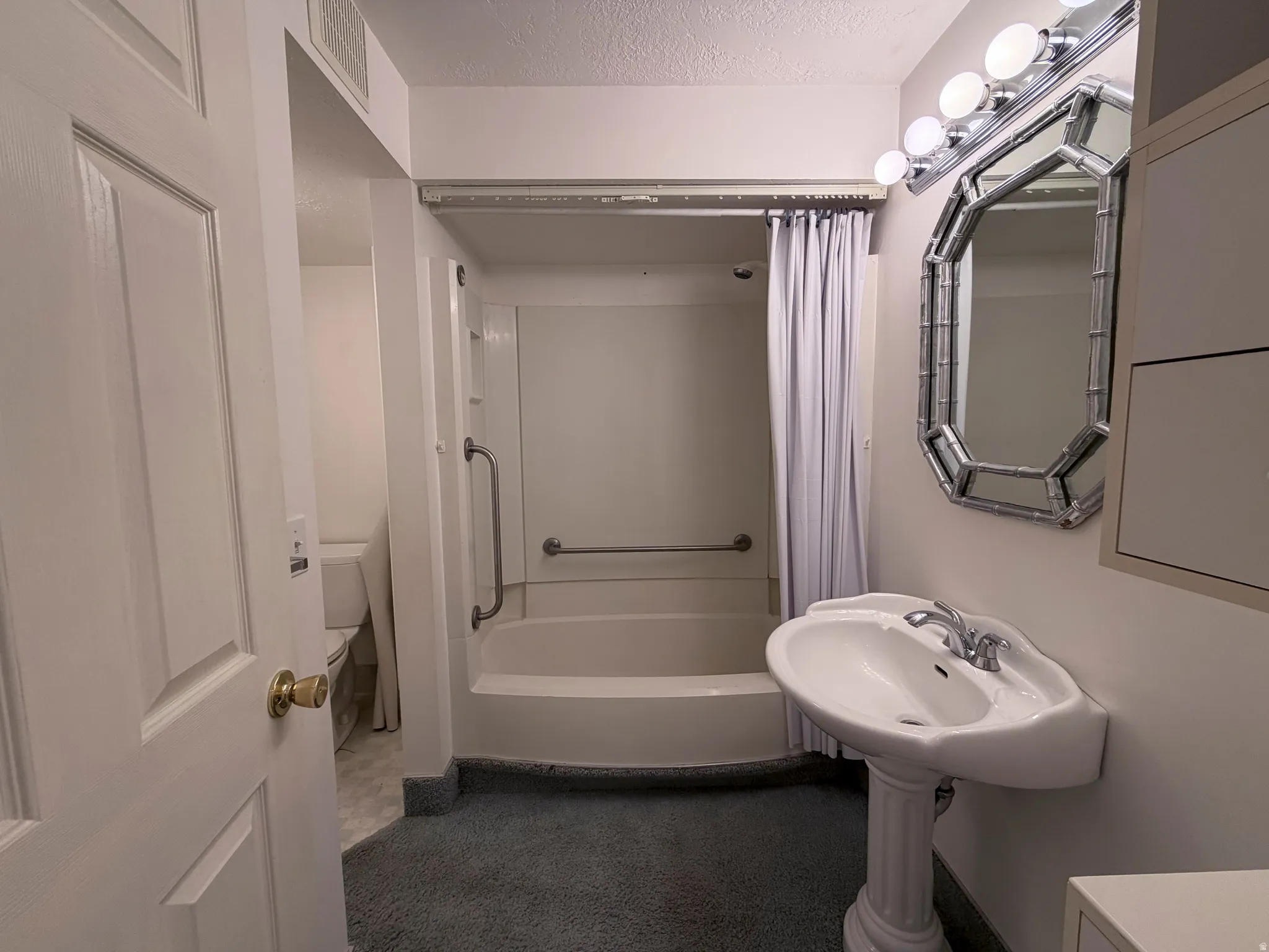 Full bathroom with a textured ceiling and shower / bath combo