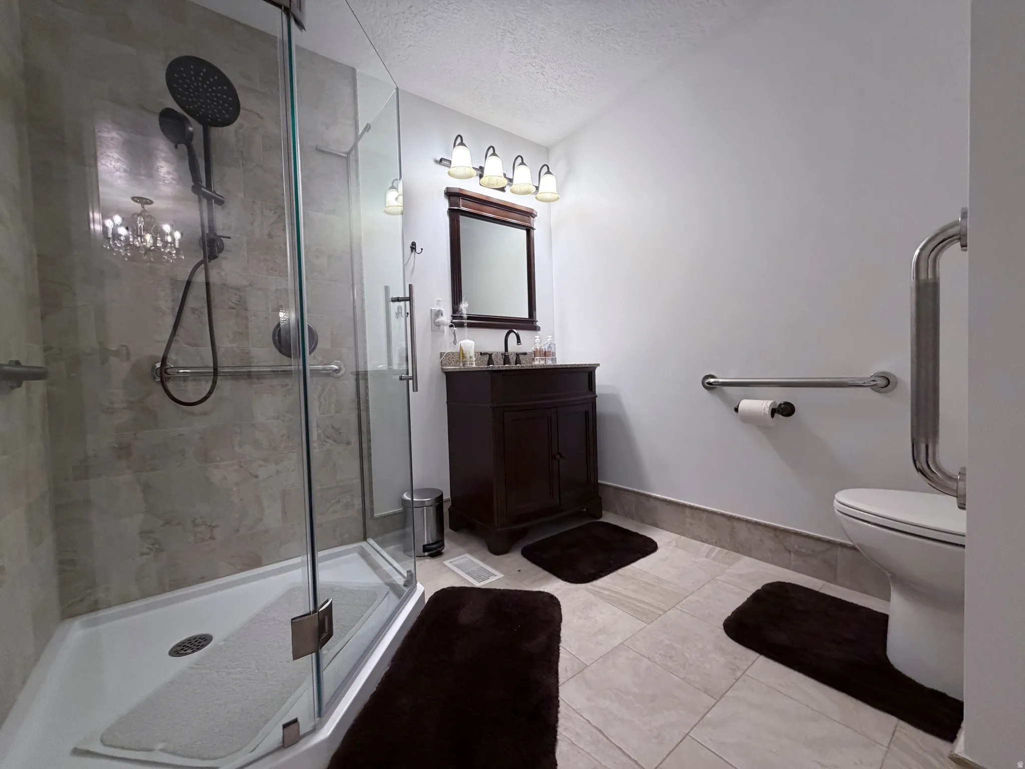 Bathroom with vanity, a textured ceiling, and a shower stall