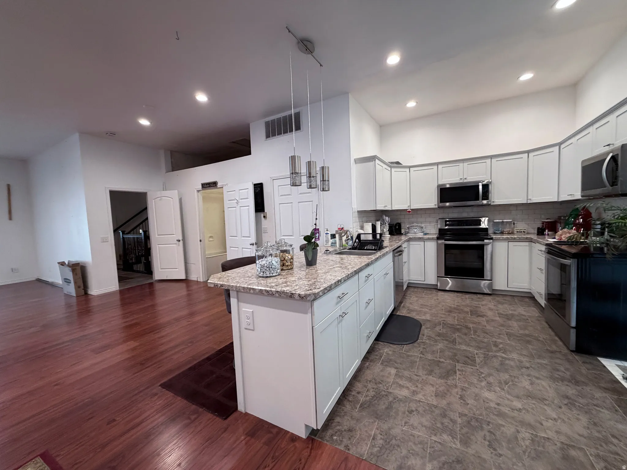 Kitchen with stainless steel appliances, light stone countertops, pendant lighting, a peninsula, and a breakfast bar