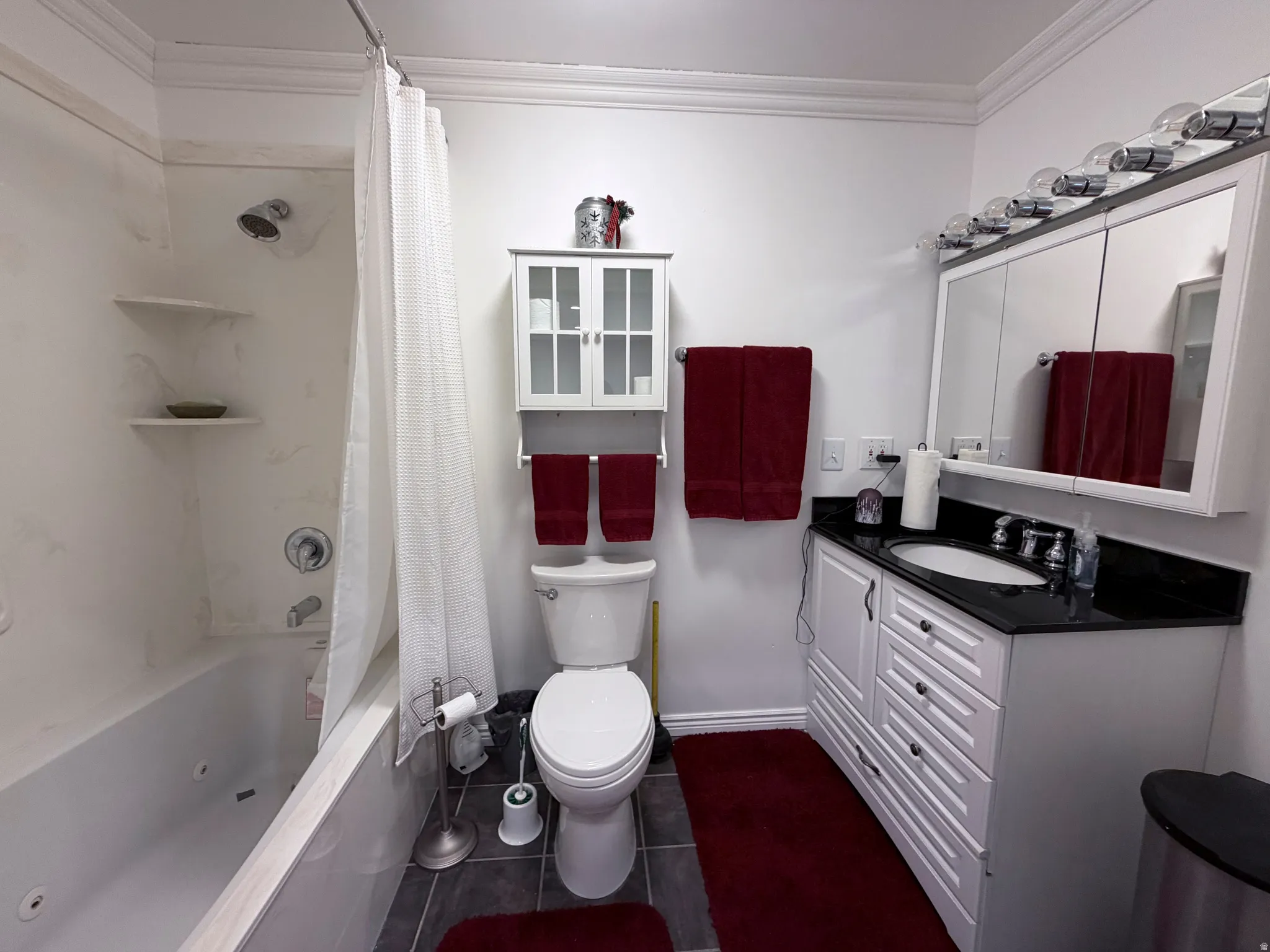 Full bath with crown molding, vanity, a combined bath / shower with jetted tub, and dark tile patterned floors