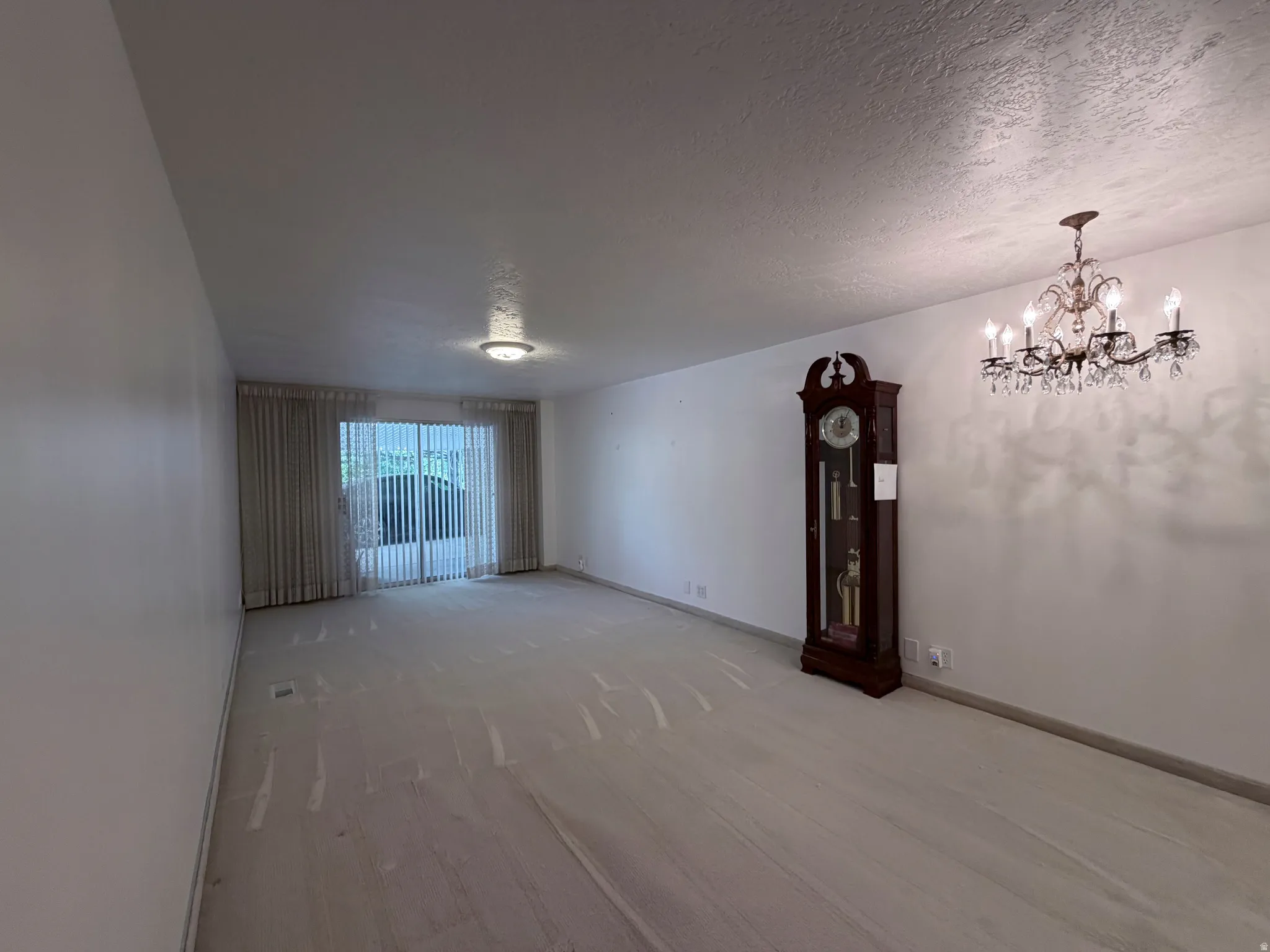 Empty room featuring a textured ceiling and suspended lighting