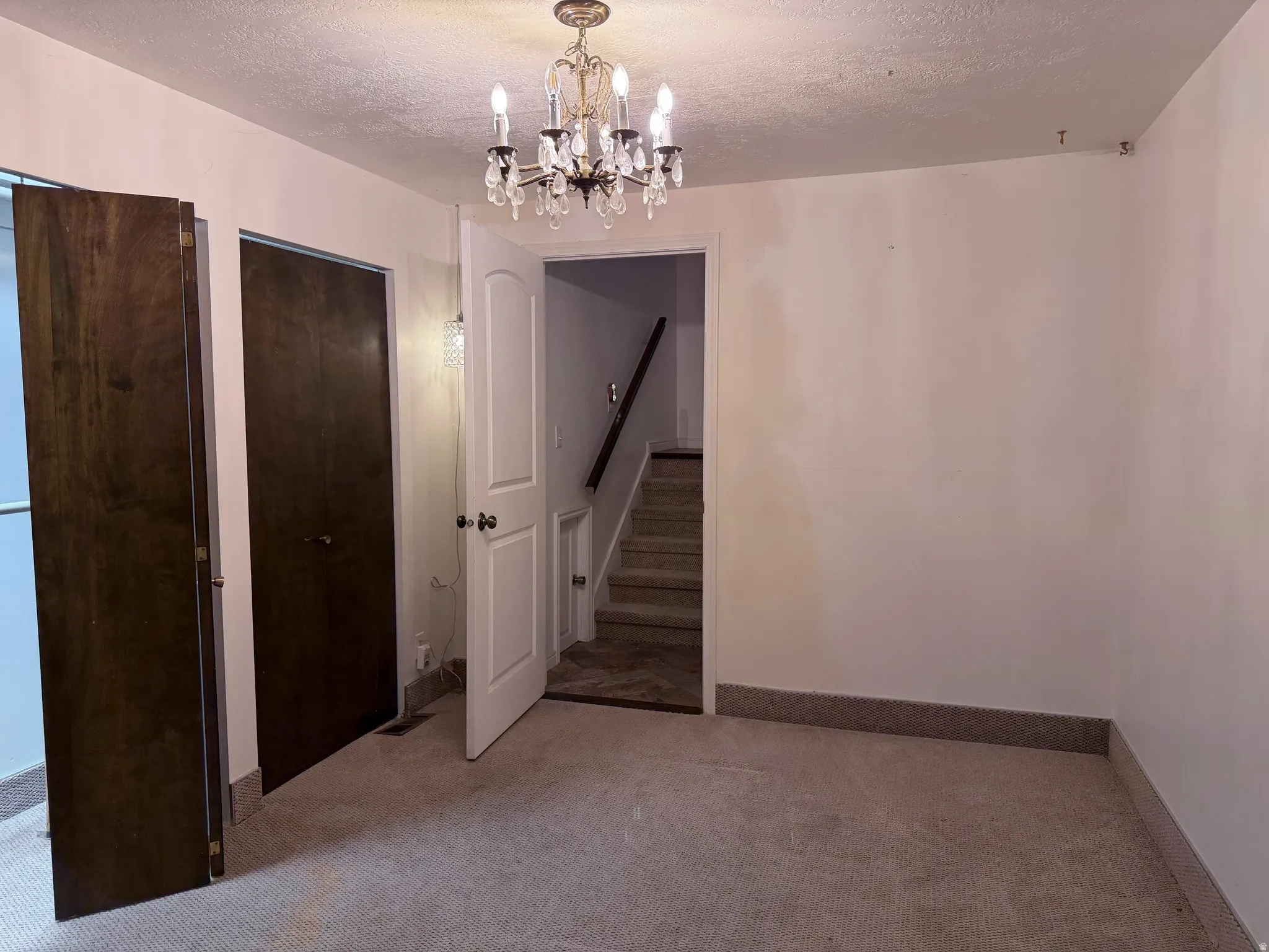 Unfurnished dining area with a textured ceiling, light carpet, and suspended lighting