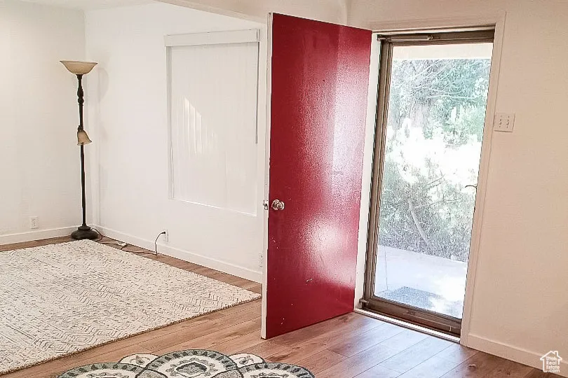Doorway to outside with wood finished floors and baseboards