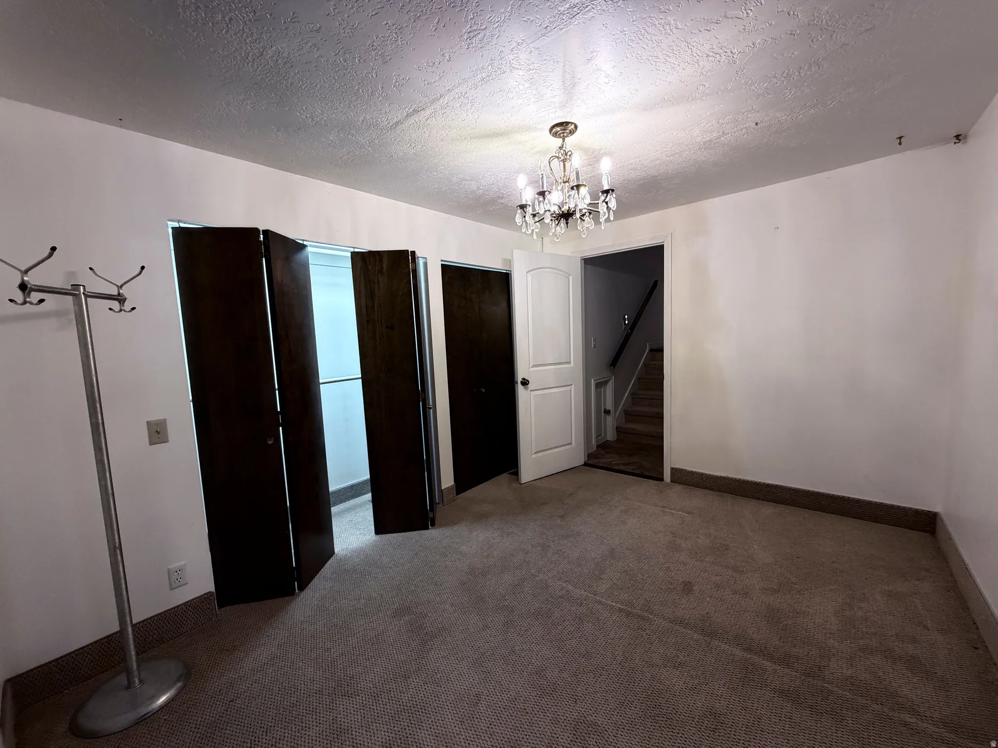Unfurnished dining area with a textured ceiling, dark carpet, and suspended lighting