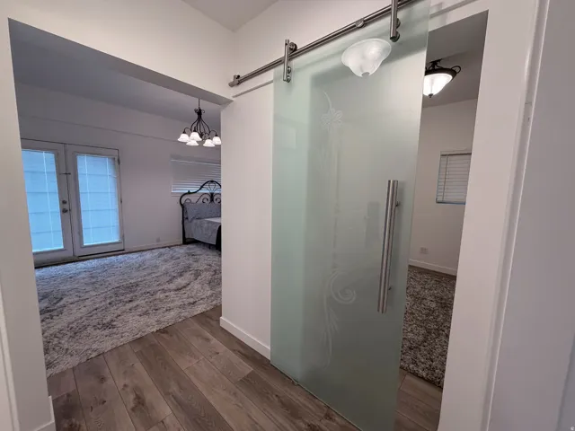 Ensuite bathroom with dark wood-type flooring, a walk in shower, and suspended lighting