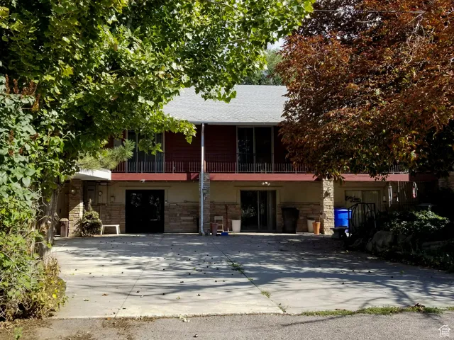 View of front of home with a balcony and stone siding