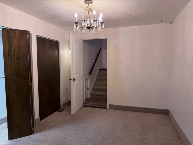 Unfurnished dining area with a textured ceiling, light carpet, and suspended lighting