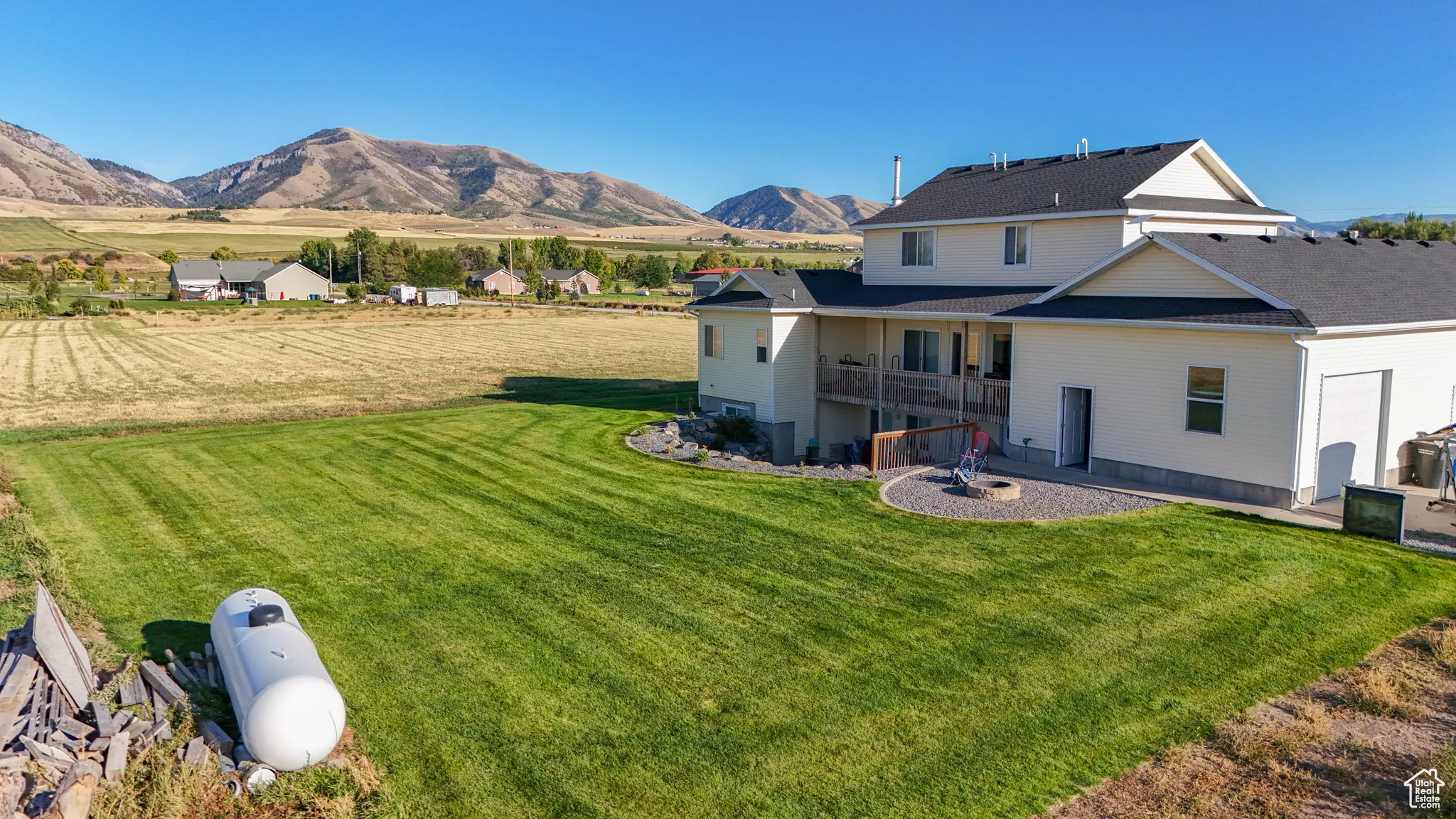 Back of house with a yard, a patio, a balcony, and a mountain view