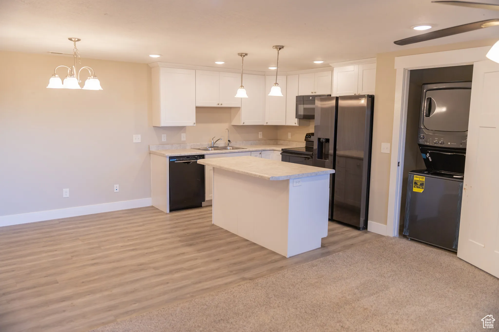 Basement apartment kitchen/dining area with white cabinets, black appliances, light countertops, recessed lighting, and hanging light fixtures
