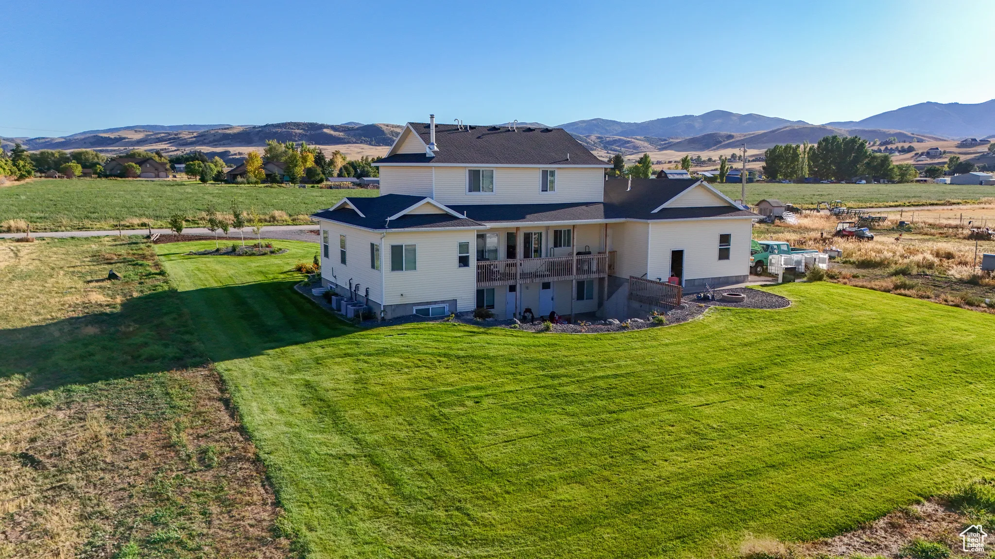 Back of property featuring a mountain view, a balcony, and a lawn
