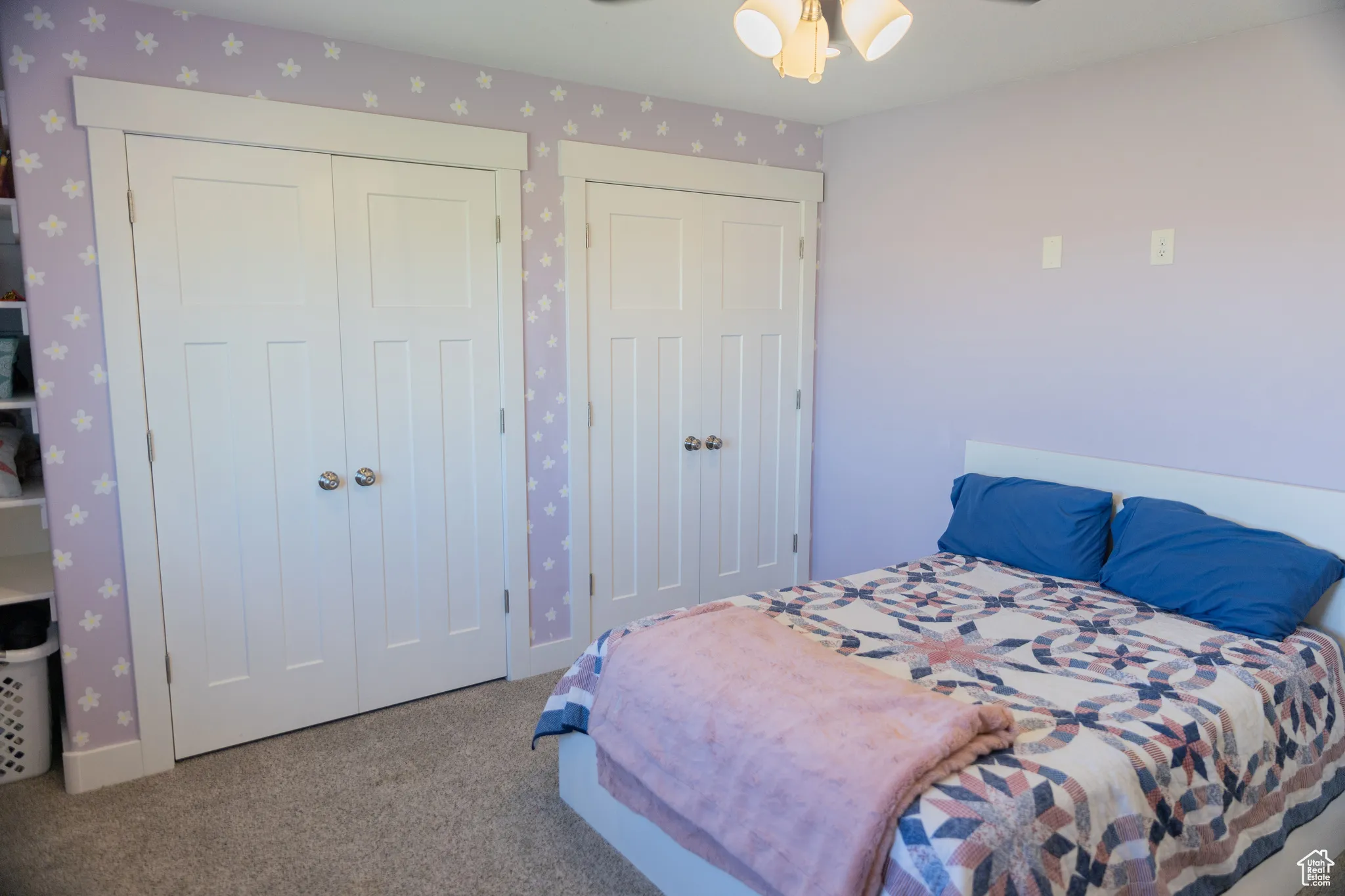 Bedroom featuring carpet, multiple closets, a ceiling fan, and wallpapered walls