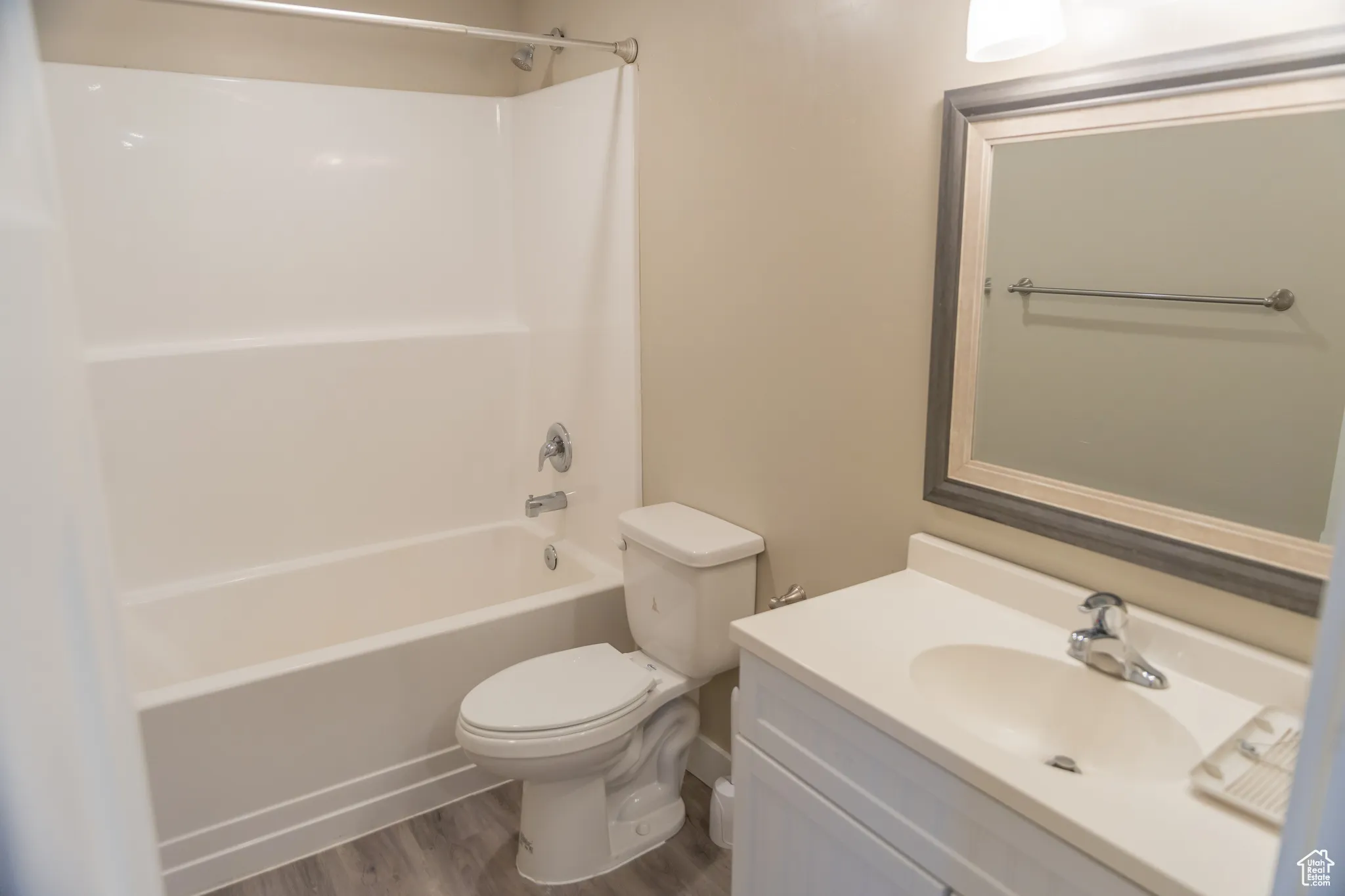 Bathroom featuring washtub / shower combination, vanity, and dark wood-style floors