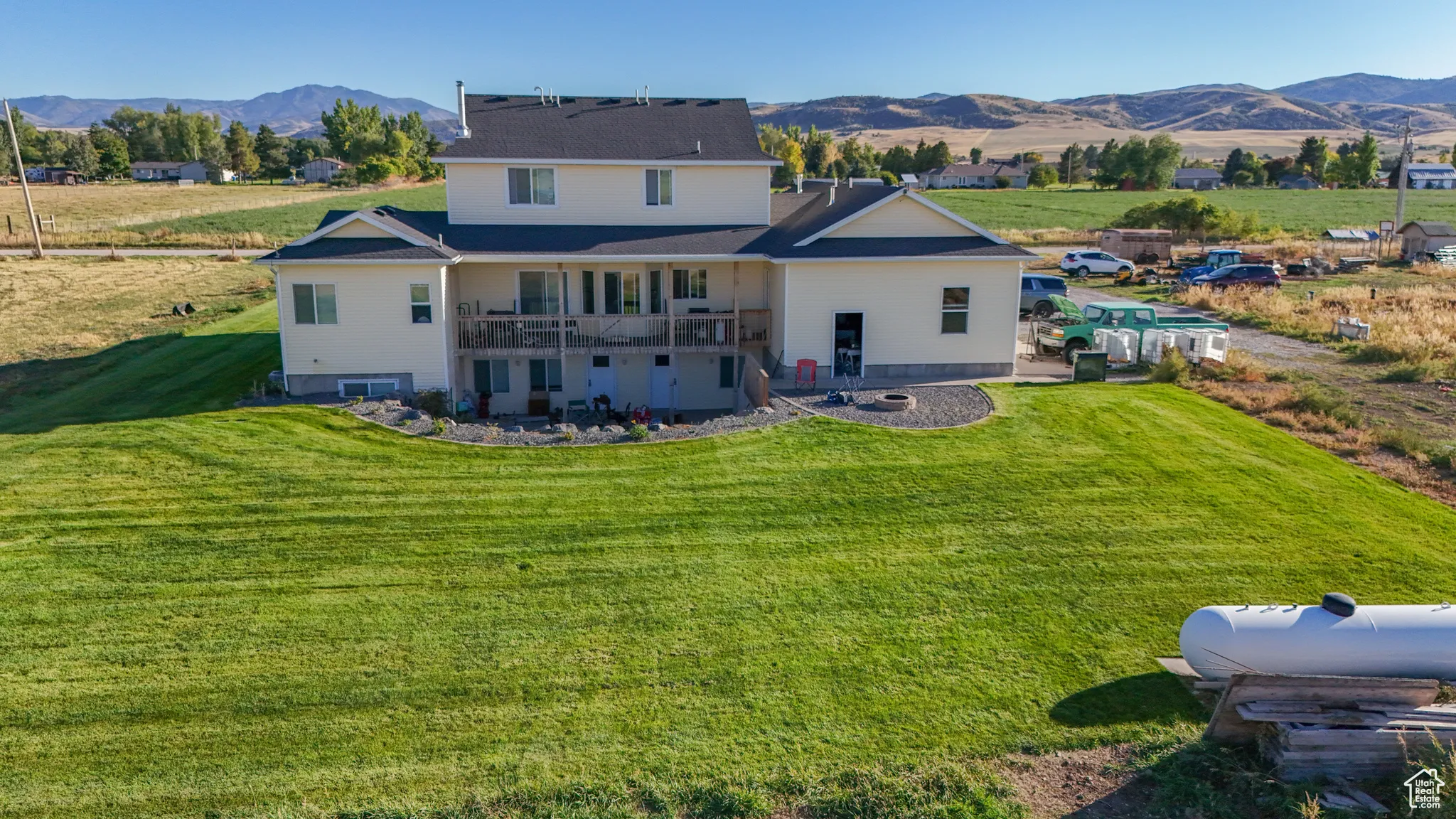 Rear view of property with a mountain view, a lawn, a balcony, and a view of rural / pastoral area