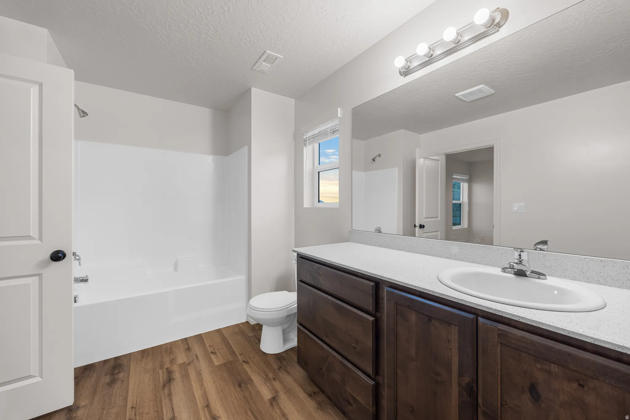 Full bathroom featuring vanity, a textured ceiling, dark wood finished floors, and shower / washtub combination