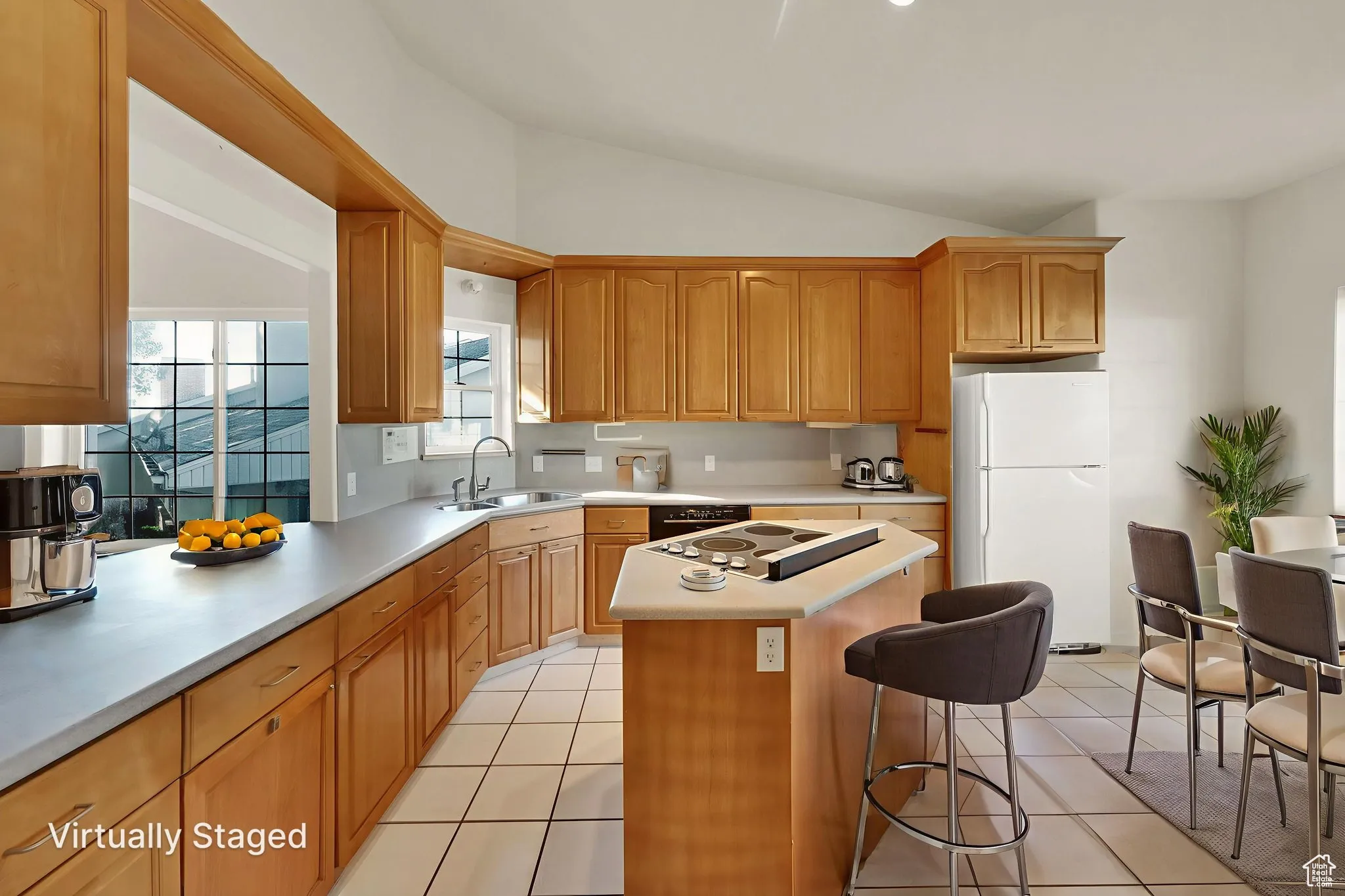 Kitchen featuring light tile patterned floors, a kitchen island, light countertops, open floor plan, and brown cabinets.