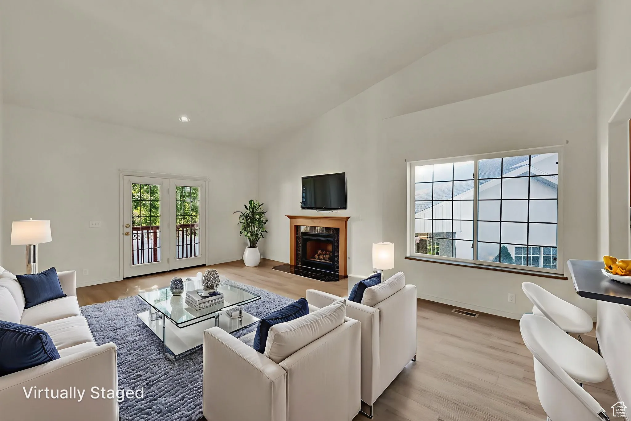 Living room with wood finished floors, a premium fireplace, lofted ceiling, and recessed lighting.