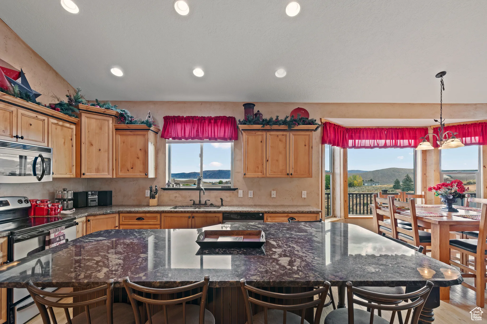 Kitchen with appliances with stainless steel finishes, dark stone countertops, a kitchen island, pendant lighting, and recessed lighting