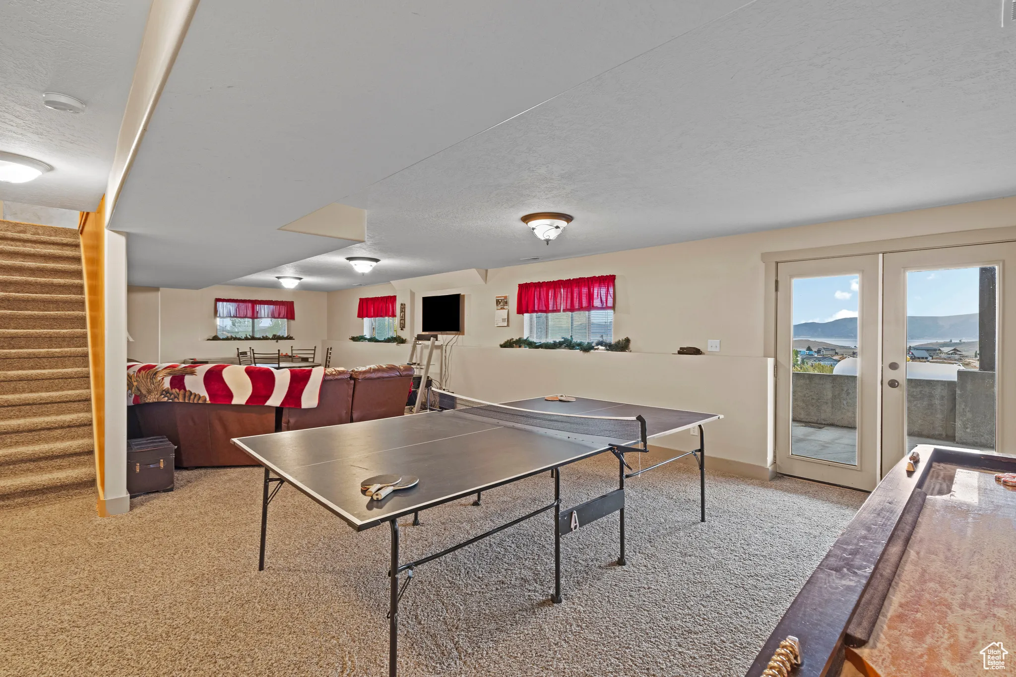 Rec room featuring light carpet, a textured ceiling, and french doors