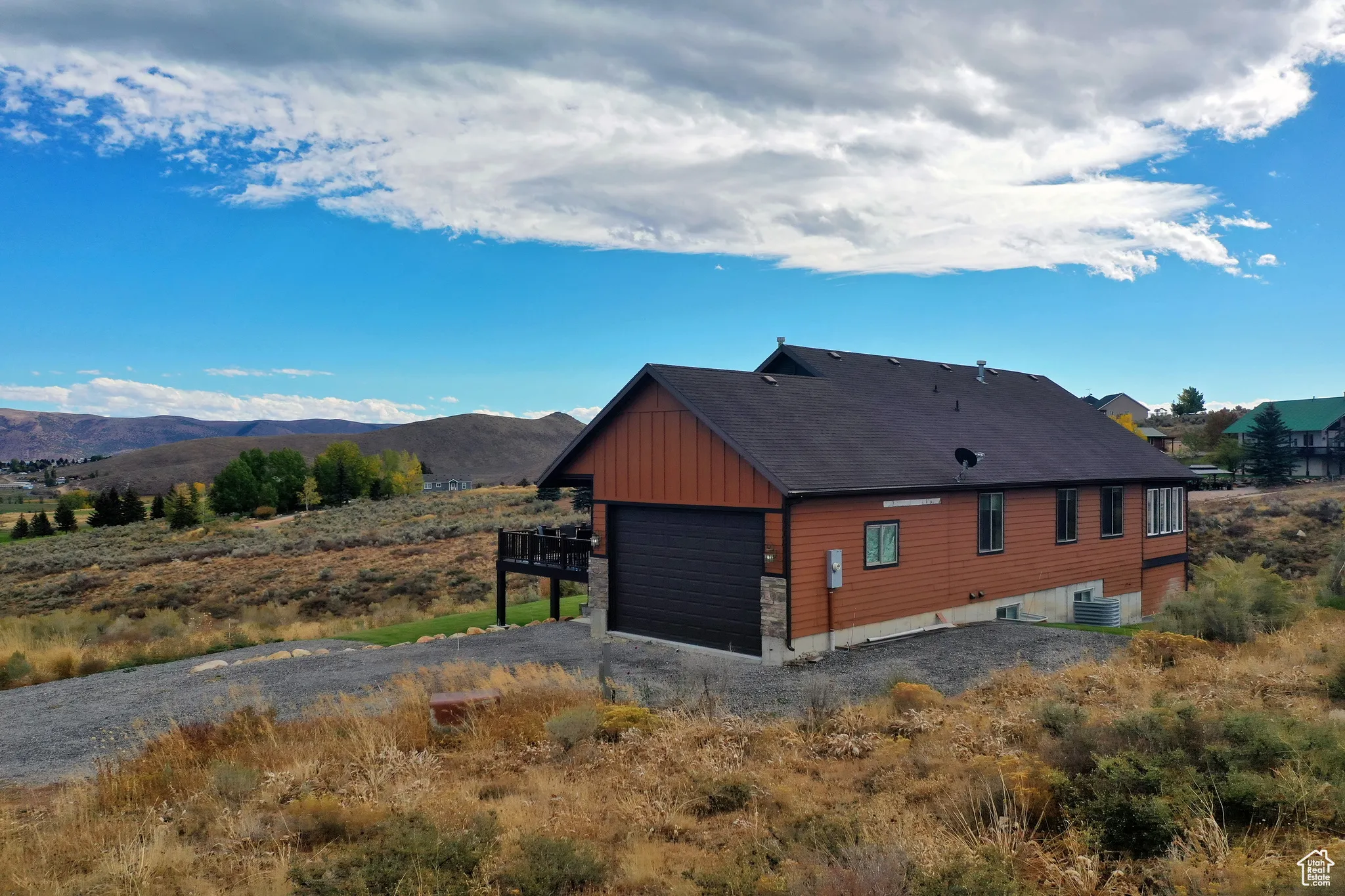 View of home's exterior with board and batten siding, gravel driveway, a mountain view, and a garage