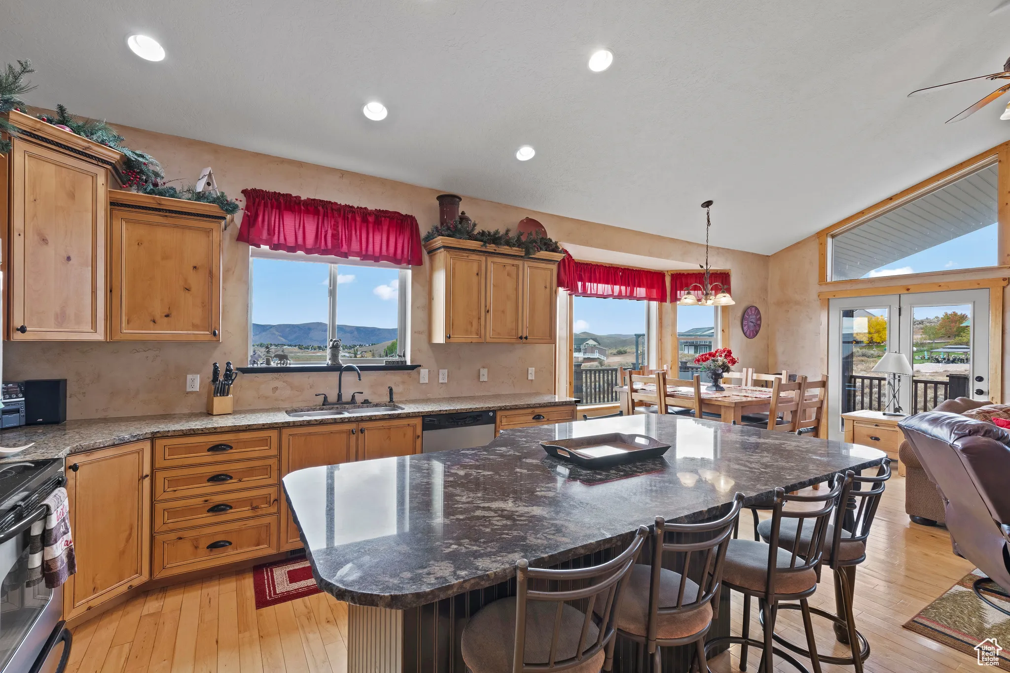 Kitchen with dark stone countertops, a center island, a breakfast bar, light wood-type flooring, and lofted ceiling