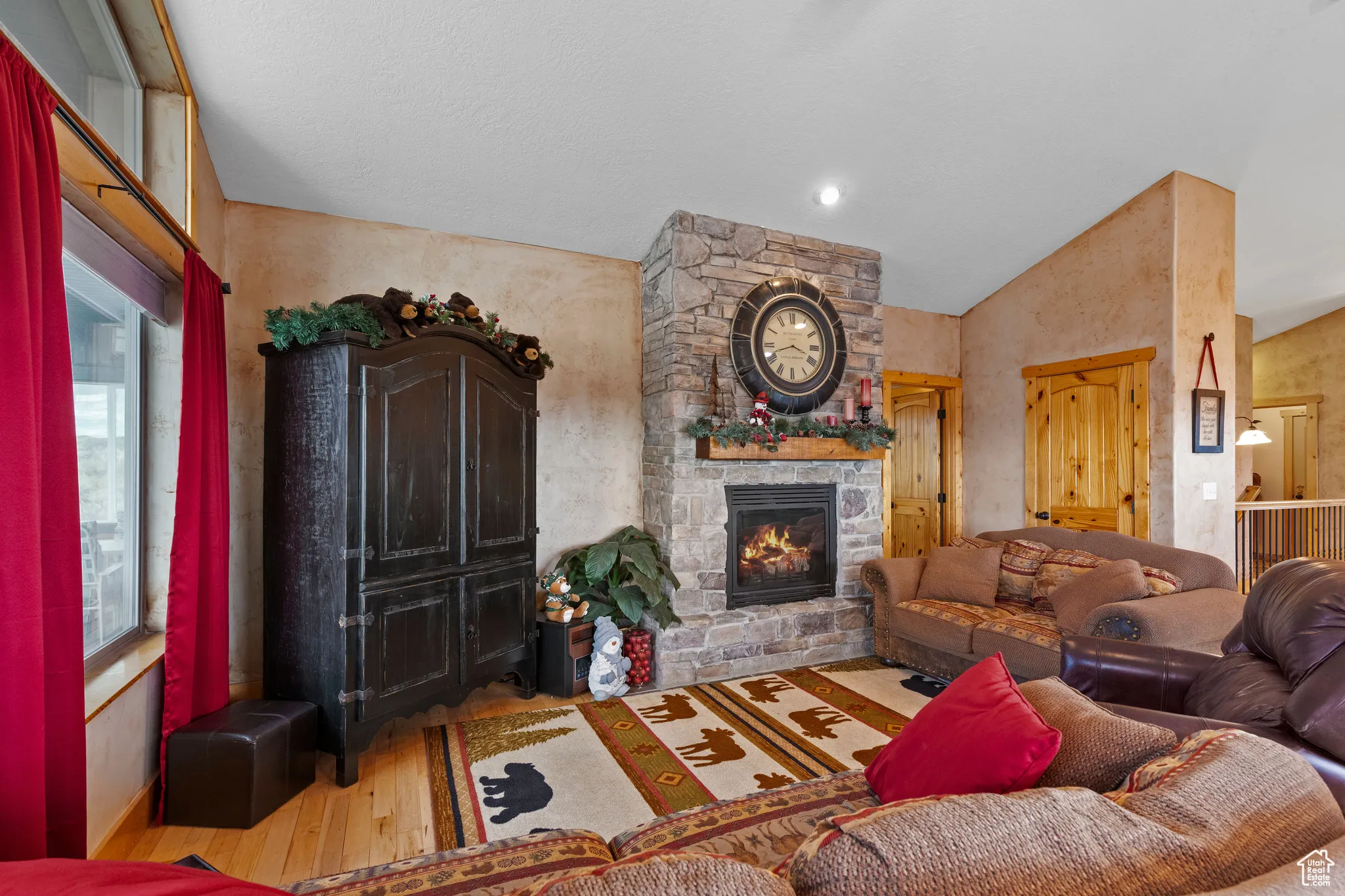 Living area with wood-type flooring, a stone fireplace, and high vaulted ceiling