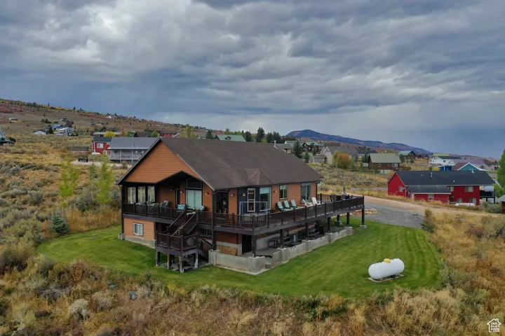 Rear view of house with a deck with mountain view and a lawn