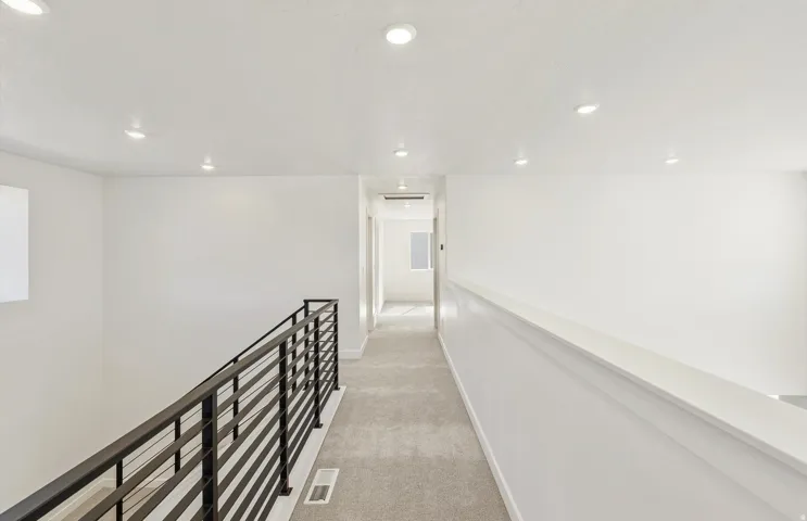 Hallway featuring light colored carpet, an upstairs landing, and recessed lighting