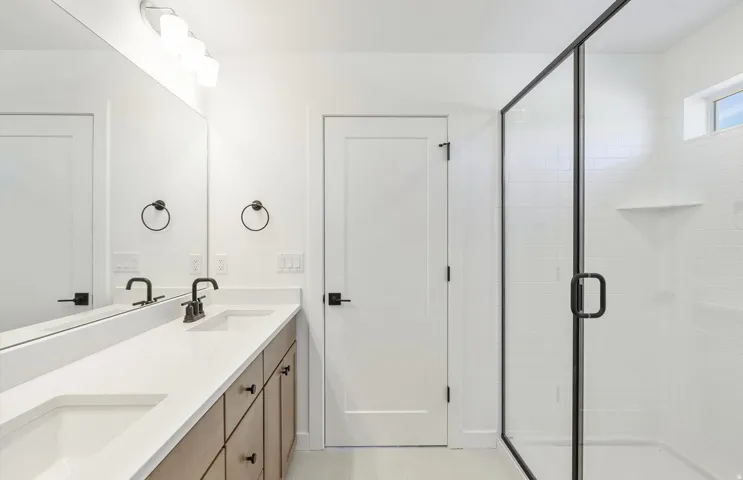 Full bath featuring double vanity and a shower stall