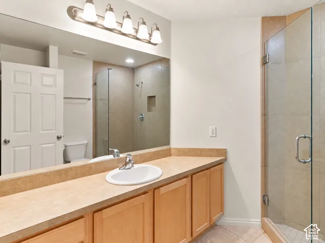 Full-width vanity with a solid-surface countertop and integrated backsplash, undermount sink, multi-light fixture, and walk-in shower with a glass enclosure