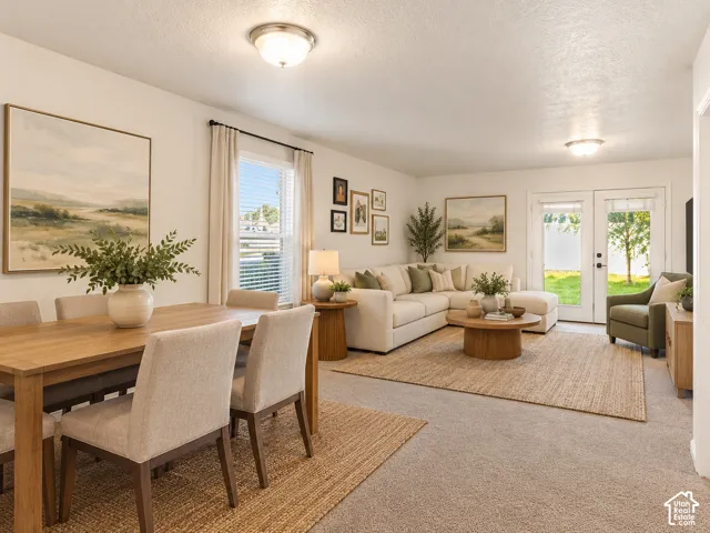 Open-concept area featuring neutral carpeting, flush-mount ceiling lighting, a single-hung window, and glass-paned double doors with exterior access