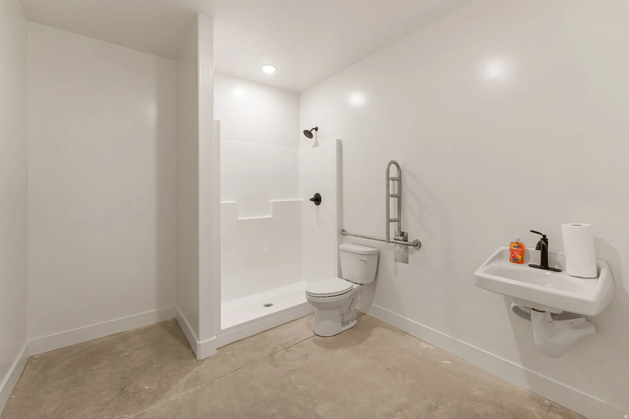Bathroom featuring unfinished concrete floors, a stall shower, and recessed lighting